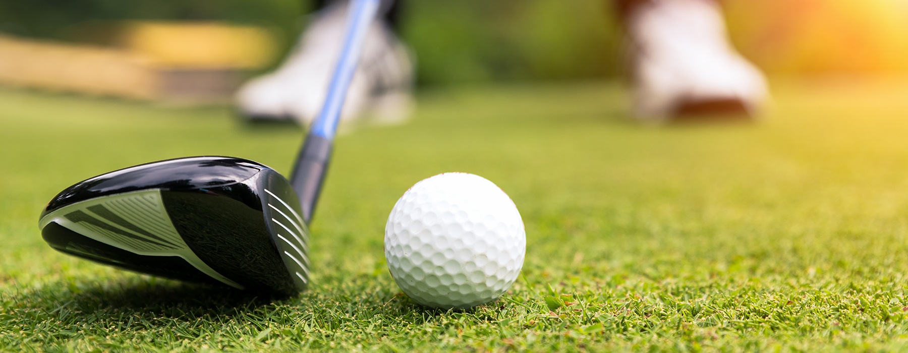 Closeup of a man about to drive a golfball 